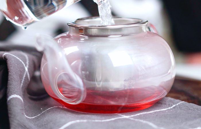 ajouter de l eau bouillante dans une théière pour faire un thé d hibiscus recette boisson ayurvédique