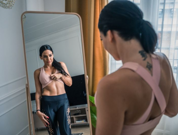 calcul deficit calorique une femme qui se regarde dans le miroir