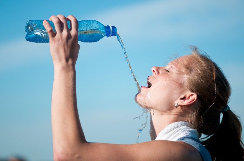 how much water to drink per day max woman drinks water from a bottle