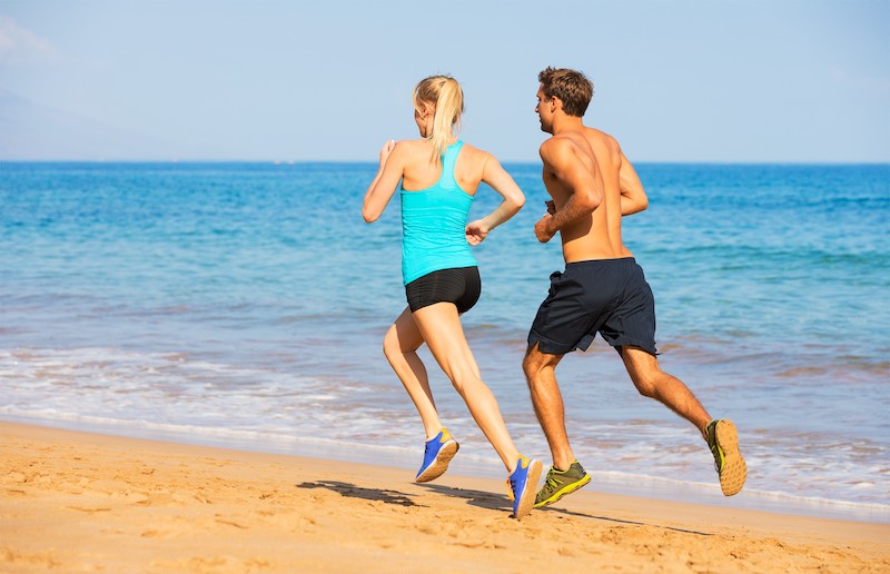 how much water should we drink per day woman and man running along the sea?