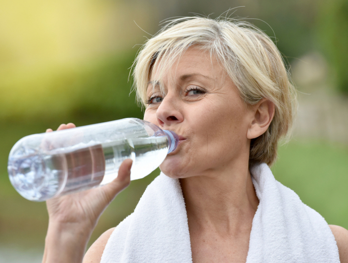 senior woman drinking water after exercising