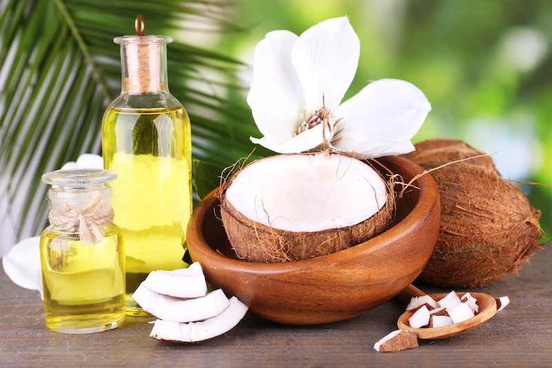 coconuts and coconut oil on wooden table, on nature background