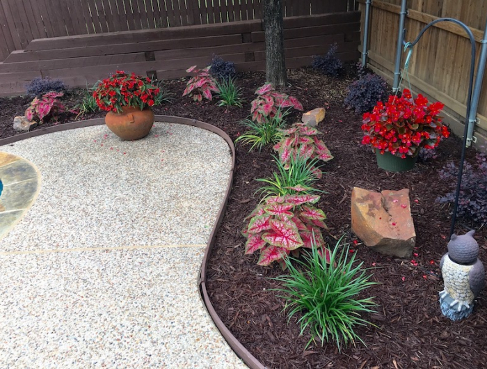 déco massif avec galets fleurs roses et rouges dans des pots avec une allee de cailloux