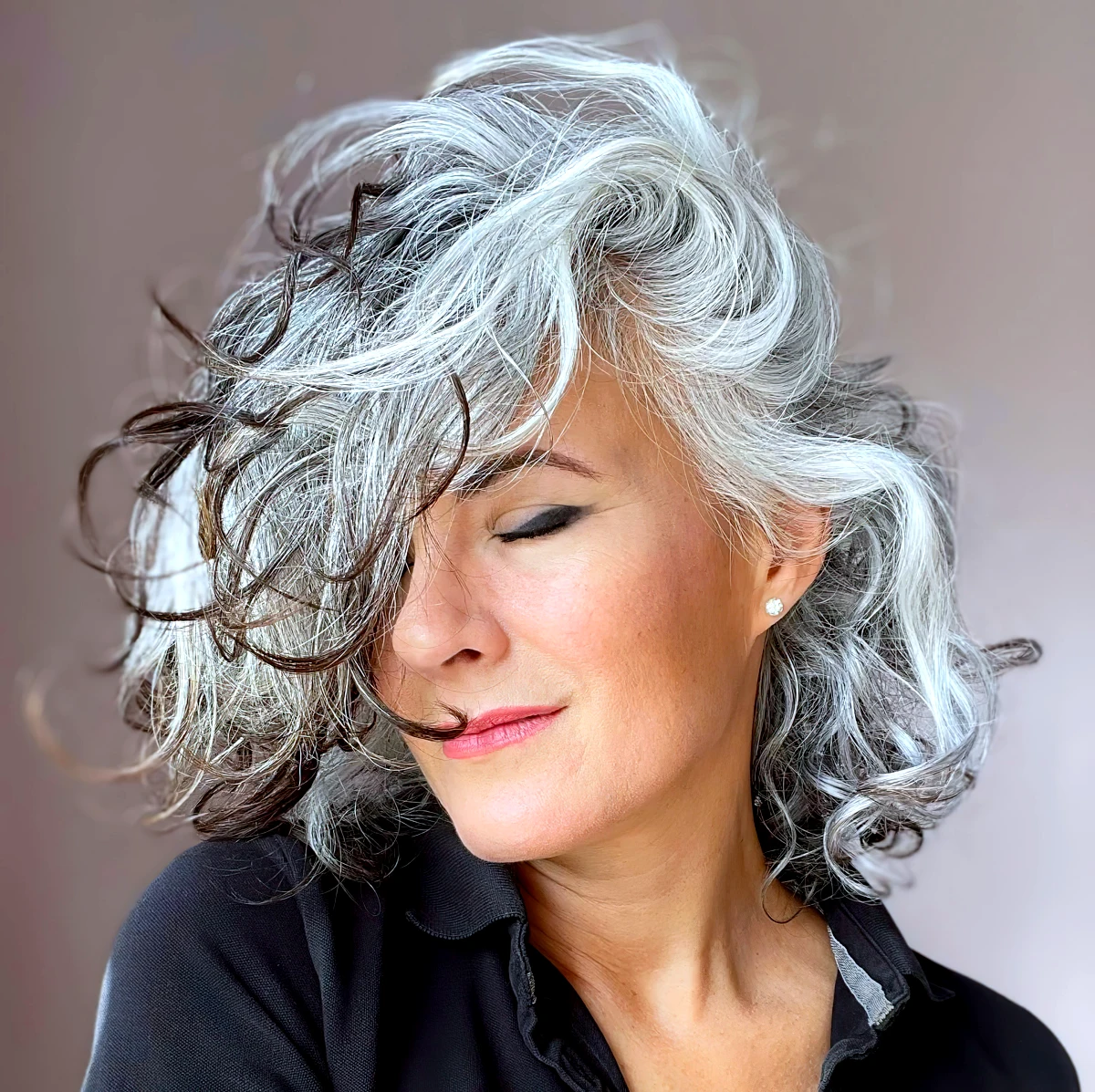 femme avec cheveux gris boucles, mettant une valeur une coiffure naurelle et elegante