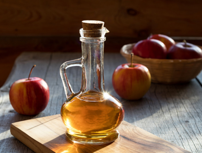 a bottle of apple cider vinegar with apples