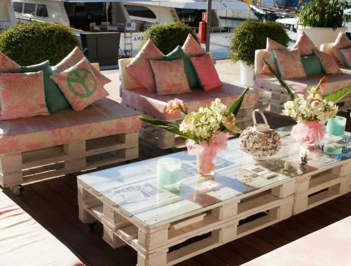 canapé jardin palette style boheme avec des tables basses et coussin rose et fleurs