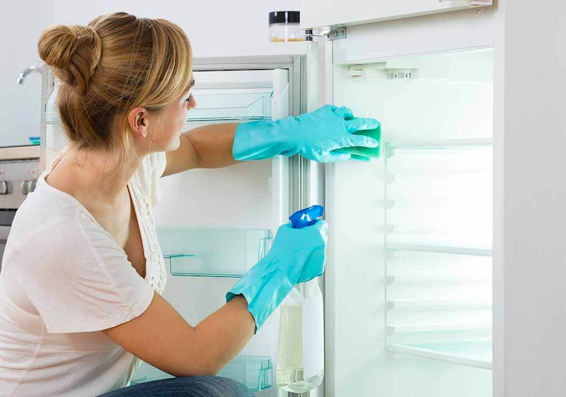 comment bien nettoyer le frigo femme au gangs bleus qui essuie