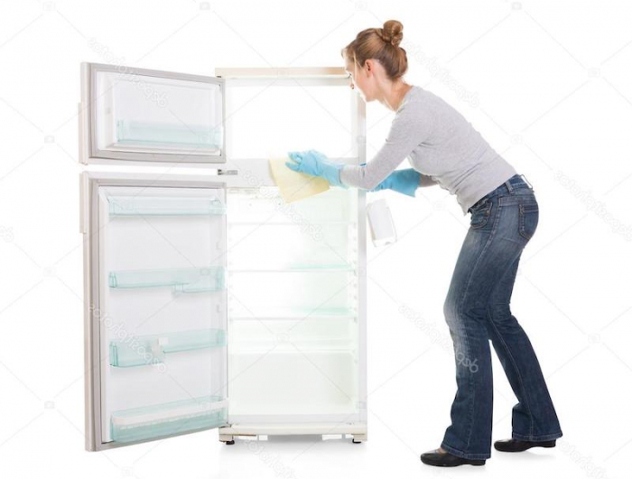 comment bien nettoyer un frigo femme au ble jean qui essuie un frigo