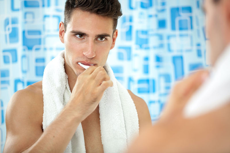 man brushing teeth in front of mirror