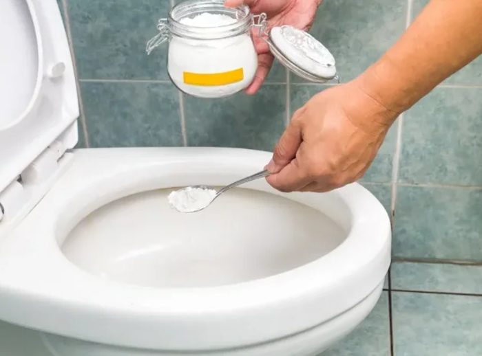 comment enlever des traces grises dans les toilettes une main met du bicarbonate a la cuvette
