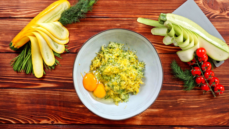 grated zucchini and two eggs in a bowl