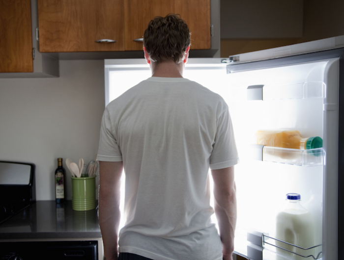 man standing looking at contents of fridge