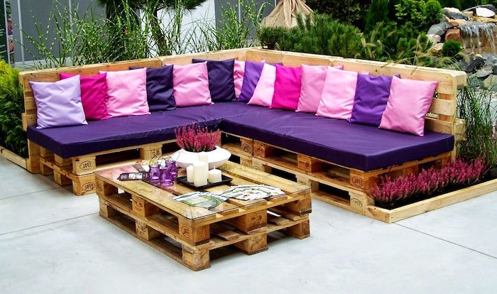 faire un salon de jardin avec palette style arty canape en bois avec coussins rose et violettes table en bois avec des bougie et des fleurs