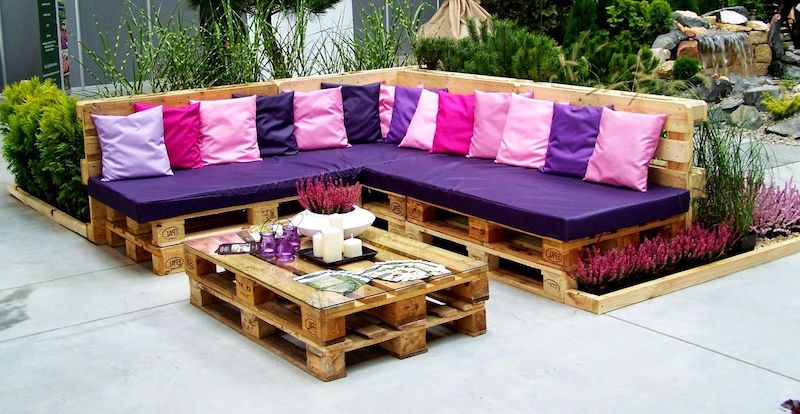 faire un salon de jardin avec palette style arty canape en bois avec coussins rose et violettes table en bois avec des bougie et des fleurs