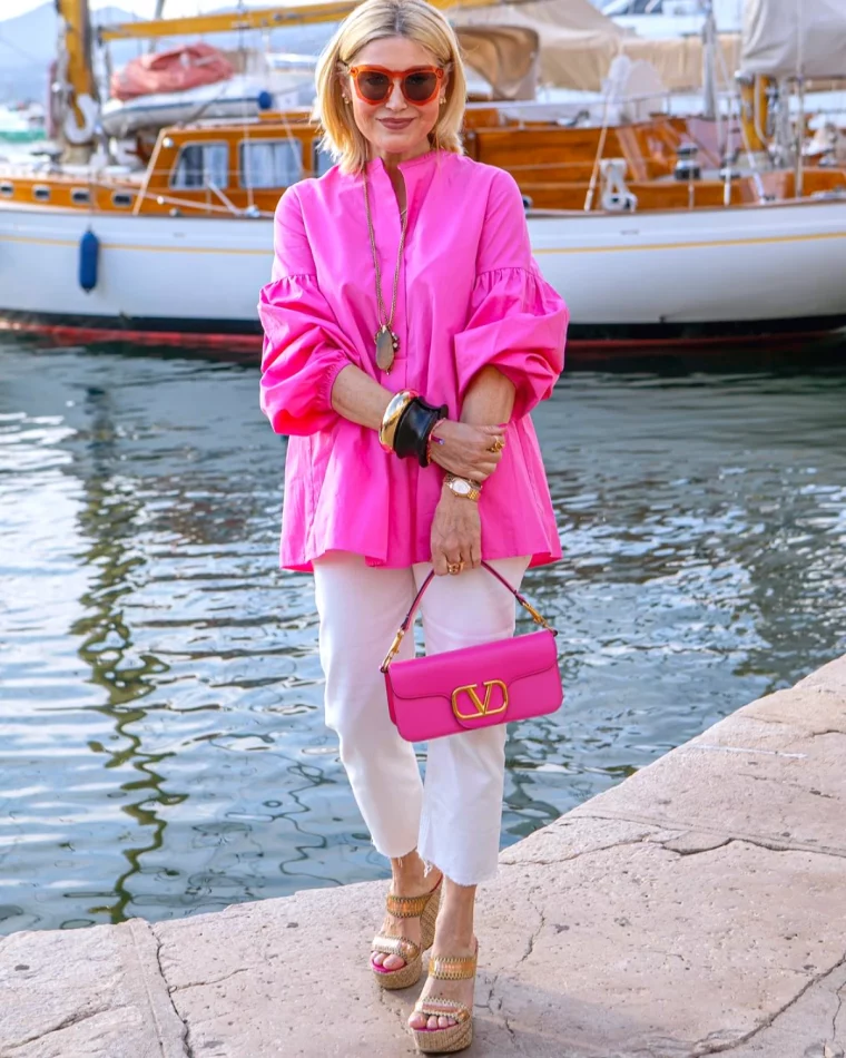 femme blonde 50 ans pantalon blanc et blouse large rose sac fuschia