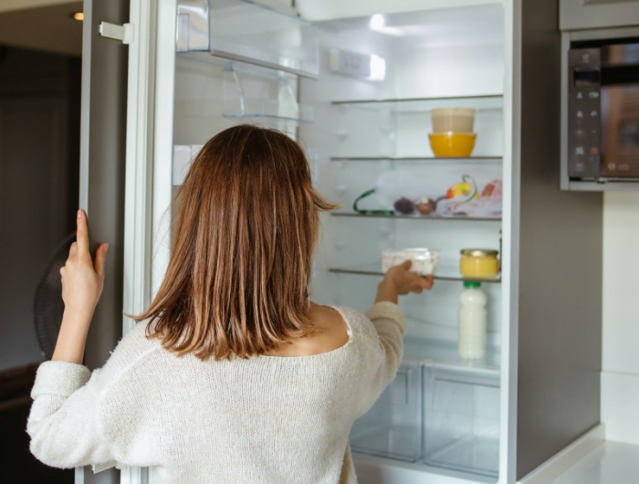 femme porte frigo ouverte nettoyage vider appareil produit maison