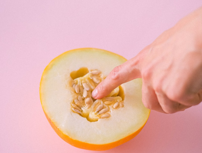 graines de melon et une main sur un fond rose