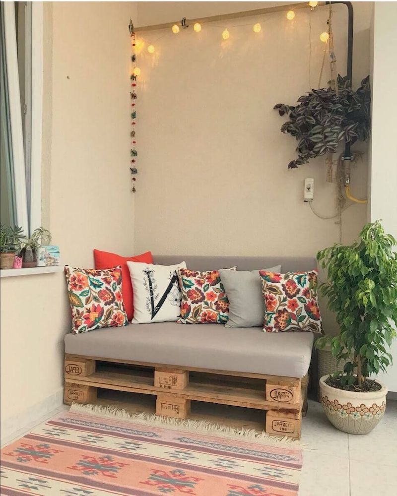 jardin en palette de bois dans un appartement petit canape en bois avec des mumieres un tapis rose et plante verte