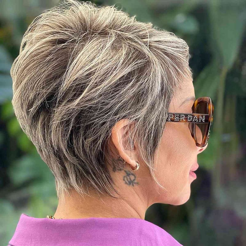 meches blondes sur une coiffure courte femme 50 ans avec lunettes volumes sur le dessus et meches autour du visage