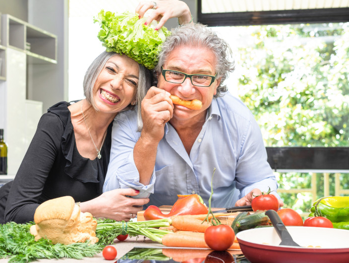 senior couple having fun in kitchen with healthy food retired people cooking meal at home with man and woman preparing lunch with bio vegetables happy elderly concept with mature funny pensioner