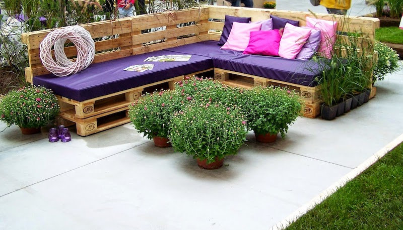 salon de jardin en palette de bois grand canape en bois avec coussins violettes et des fleurs autour