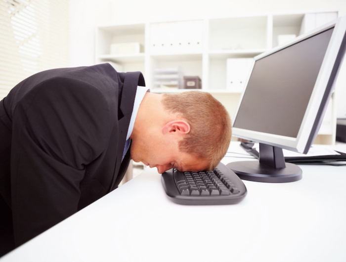 portrait of a stressed businessman with his forehead resting on the computer keyboard