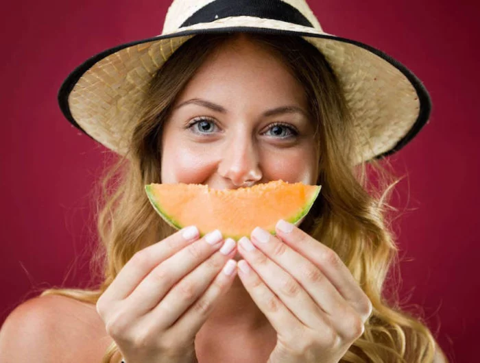 melon calorie regime une femme tenat un melon devant la bouche avec un chapeau