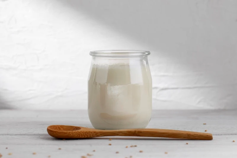 un yaourt naturel blanc avec une cuilliere en bois