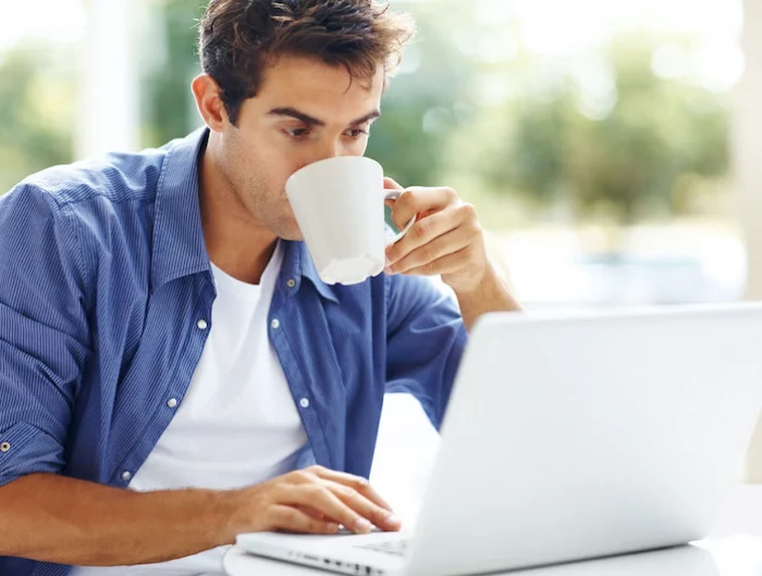 boire cafe cholesterol tension sanguine dangers jeune homme devant ordinateur blanc boit du cafe