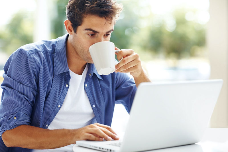 boire cafe cholesterol tension sanguine dangers jeune homme devant ordinateur blanc boit du cafe