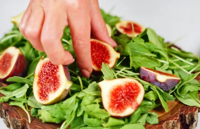 salade verte figues coupees en deux main
