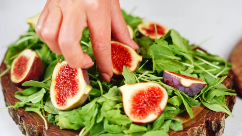 salade verte figues coupees en deux main