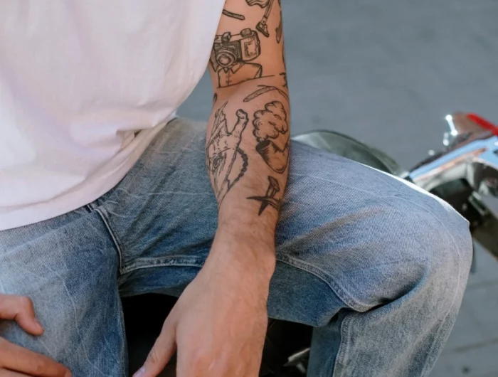 tatouage homme bras motifs astrologie main jeans t shirt blanc