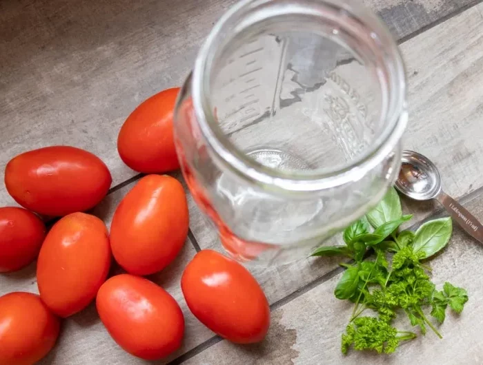 un bocal en verre vide avec des tomates fraiches et du basilic