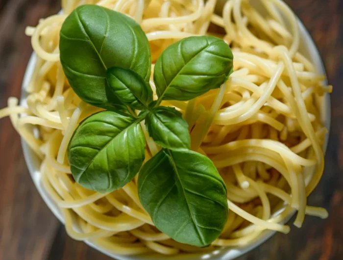un plat de spagetti avec des feuilles de basilc frais