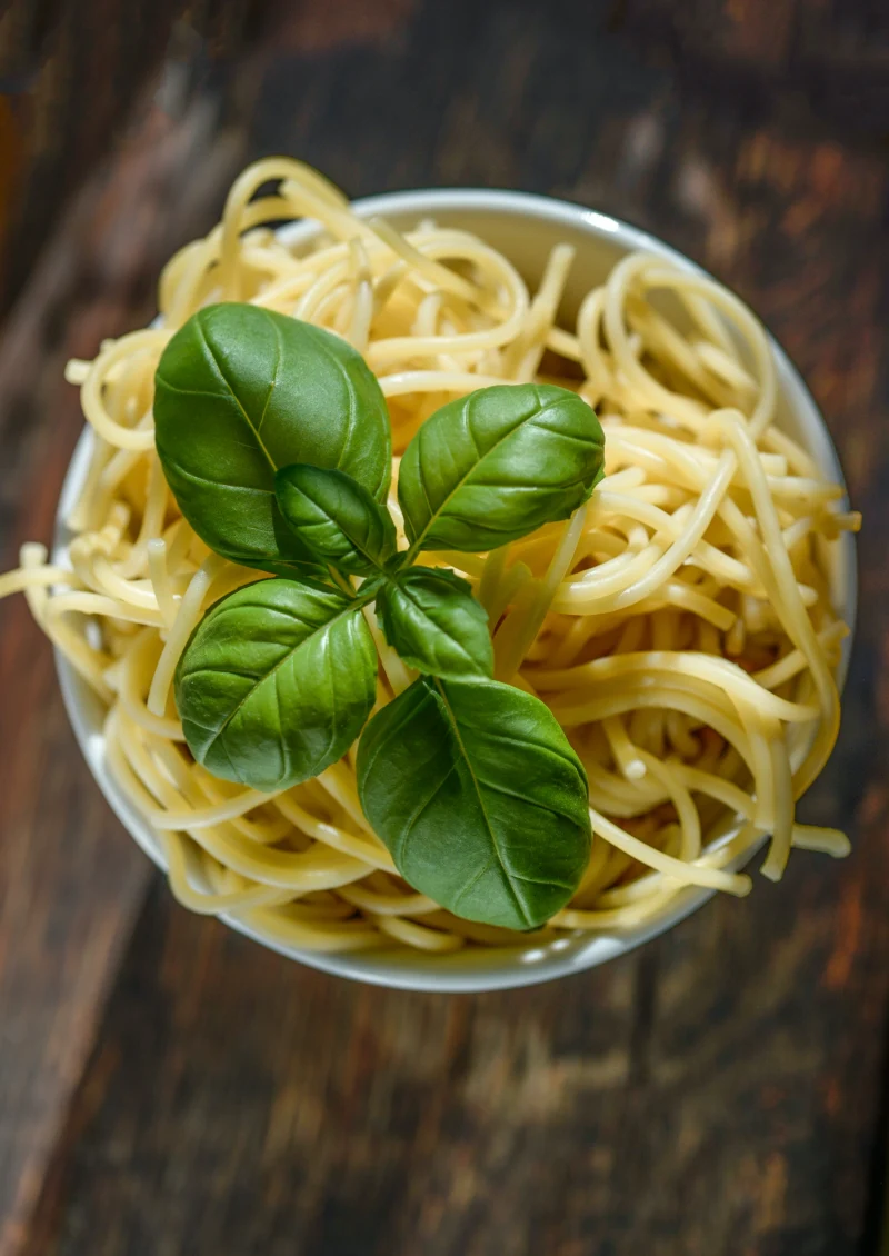 un plat de spagetti avec des feuilles de basilc frais