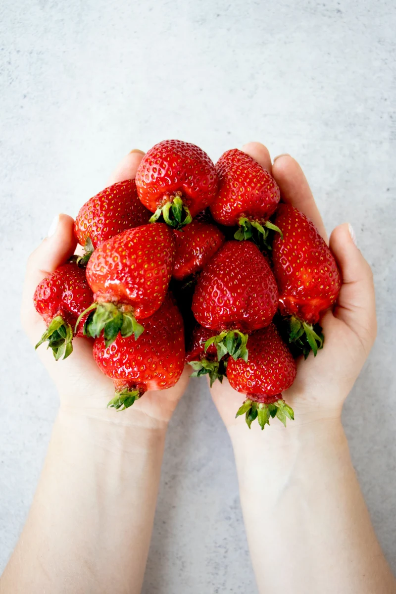 une main qui tient des fraises rouges