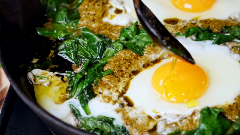 Pour olive oil over eggs in a frying pan