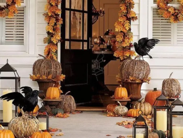 citrouilles oranges et enpaillees avec deux courbeaux devant une porte decoree de feuilles mortes