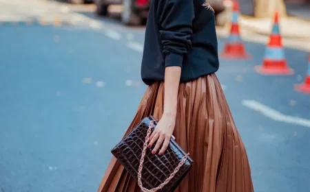 comment porter une jupe en cuir marron plissée et pull noir sac à main noir