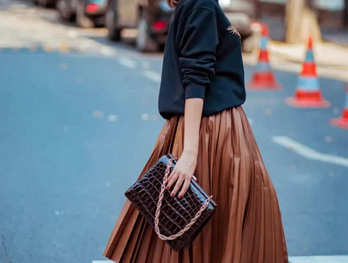 comment porter une jupe en cuir marron plissée et pull noir sac à main noir