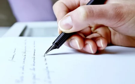 main qui ecrit avec un stylo a encre sur une feuille blanche