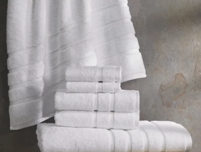 une serviette acrochee sur fond gris et des serviettes pliees sur un meuble eu bois claire