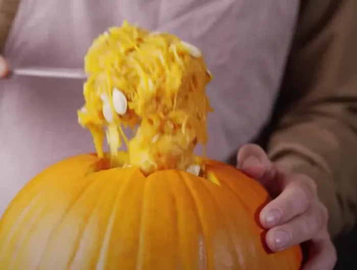 vider une citrouille orange de ses grains avec une main