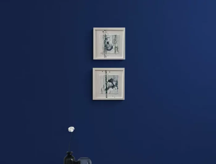 bleu fonce avec deux petits tableaux au mur derriere un meuble blanc avec un livre ouvert