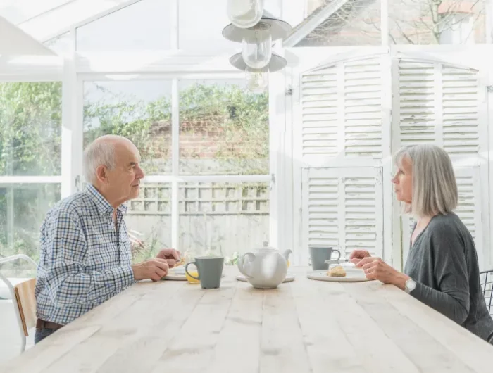 couple qui evite le conflit assis sur table en face a face dans une ambiance interieure blanche