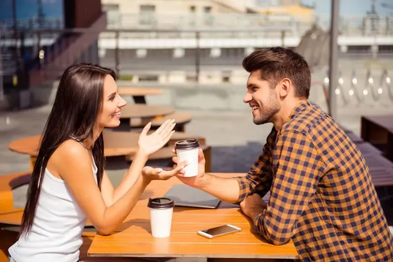 couple qui parle et boit du cafe assis sur table e terrasse