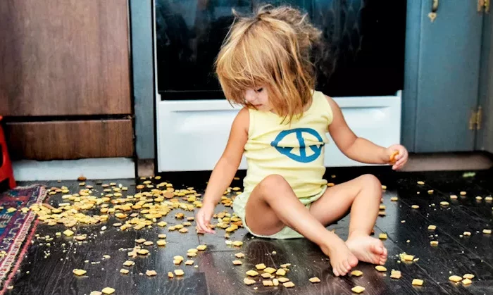 enfant joue et mange du snack par terre