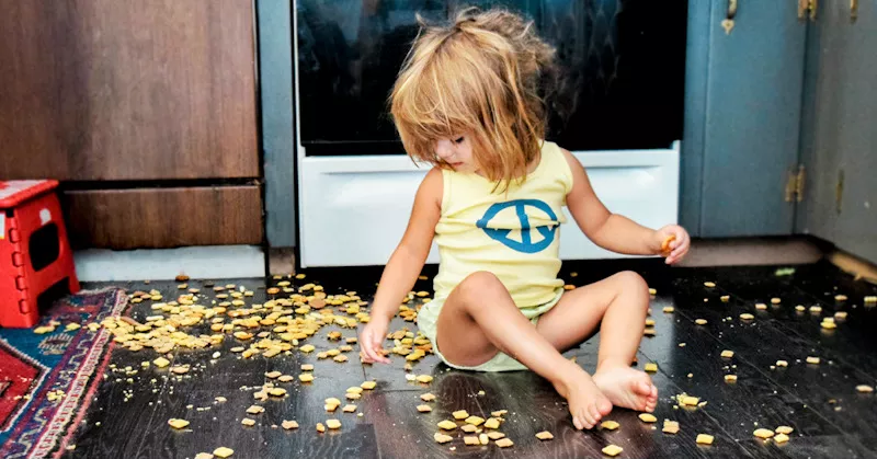 enfant joue et mange du snack par terre