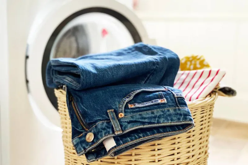 jeans plie dans un panier traisse devant un lave linge